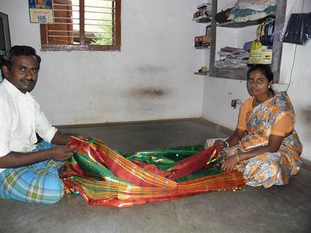 A saree being folded and rolled flat by hand after pressing