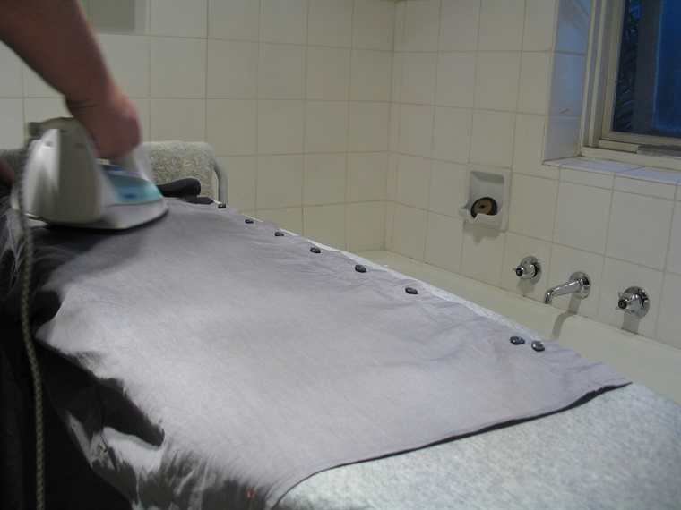 A shirt being pressed with an iron on a padded board